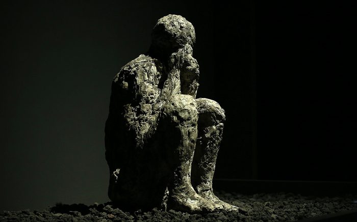 The cast of a sitting man covering his nose and mouth with his hands at the time of the volcanic eruption. 