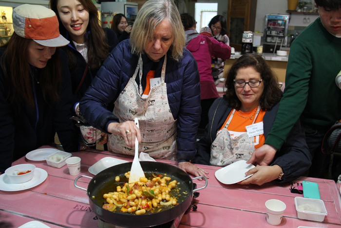 (Top) Participants stretch a ball of mozzarella, adding salt as they do so. (Bottom) Tour participants fry up some rice cake and other ingredients to make cheese <i>tteokbokki</i>. 