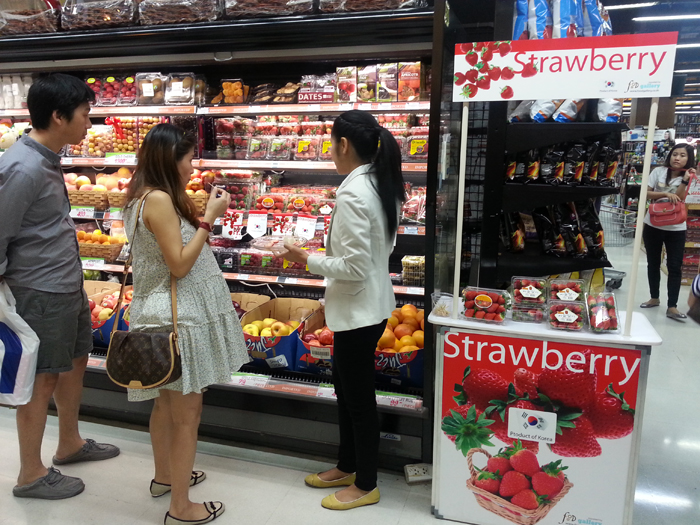 Shoppers sample Korean strawberries in Thailand.