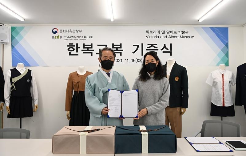 Korea Craft and Design Foundation (KCDF) Director Kim Tae-hoon on Nov. 16 at the Hanbok Advancement Center in Seoul presents a certificate on the donation of two Hanbok-inspired uniforms to Rosalie Kim, lead curator of a Hanbok exhibition at Victoria and Albert Museum in London. (KCDF) 