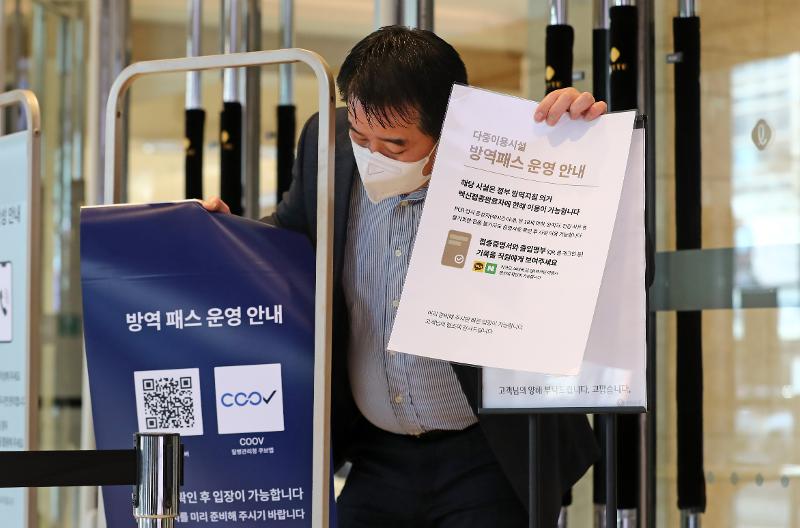 The lifting of the vaccine pass system of presenting vaccination verification or a negative result of a COVID-19 test took effect on Jan. 18 at six types of multi-use facilities such as department stores and large supermarkets. The photo shows a staff member at Lotte Department Store in Daejeon on Jan. 17 removing signs on the pass in front of the entrance. (Yonhap News)