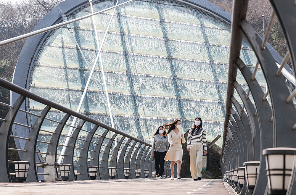 Visitors amid perfect spring weather on the morning of April 4 walk across Aqua Art Bridge on Nambusunhwan-ro Road in front of the Seoul Arts Center in the city's Seocho-gu District.