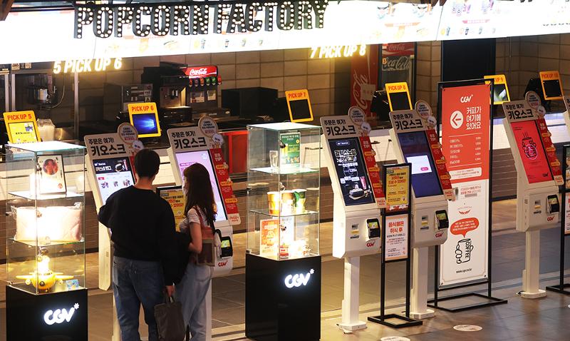The Central Disaster and Safety Countermeasures Headquarters from April 25 allowed the consumption of food inside indoor facilities such as movie theaters and supermarkets. Shown are people on the day before ordering popcorn and soft drinks at the concessions section of a movie theater in Seoul. (Yonhap News)