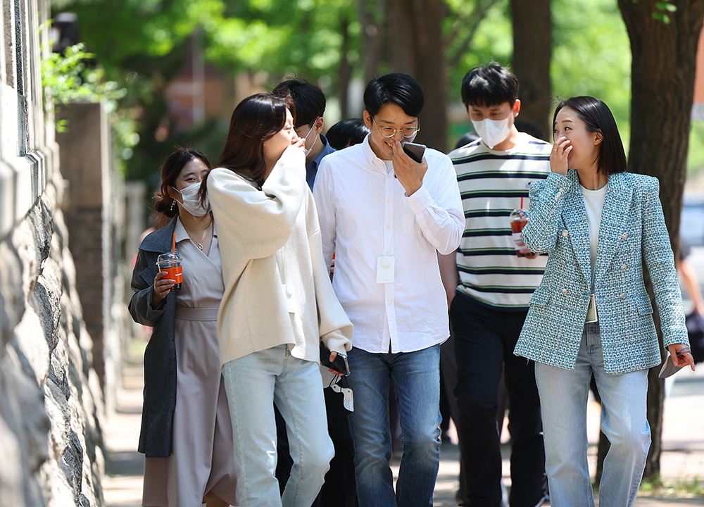 Office workers without masks on May 2, the day when the outdoor mask mandate was lifted, take a walk on the trail Jeongdong-gil in Seoul's Jung-gu District. 