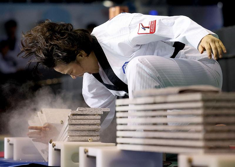 A member of the Kukkiwon Taekwondo Demonstration Team on June 16 smashes pine boards at the ceremony for the unveiling of the bust of Kim Un-yong, the first president of the World Taekwondo Federation (now World Taekwondo), at Kukkiwon, aka World Taekwondo Headquarters, in Seoul's Gangnam-gu District.