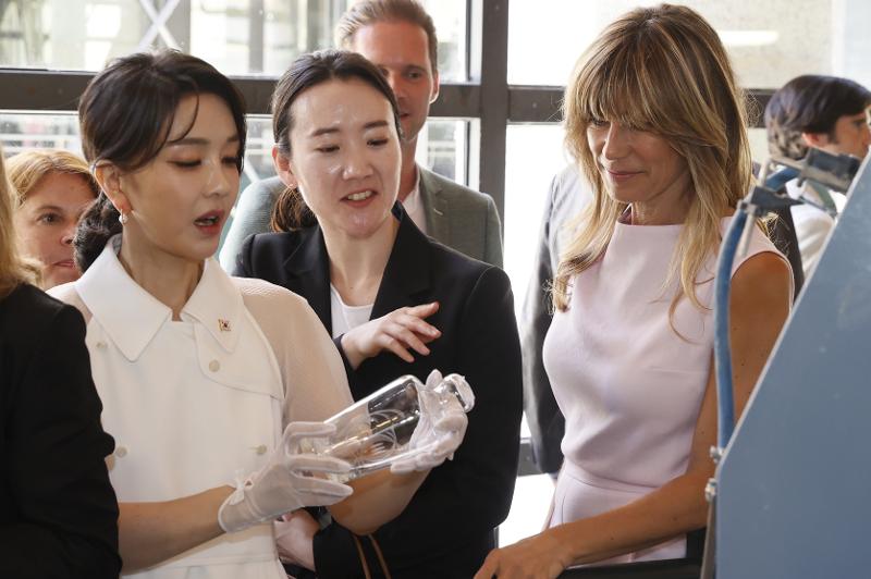 First lady Kim Keon Hee (left) on June 29 examines a glass artifact at the Royal Glass Factory of La Granja in Segovia, a historical city northwest of Madrid, with the spouses of other leaders attending the NATO summit.