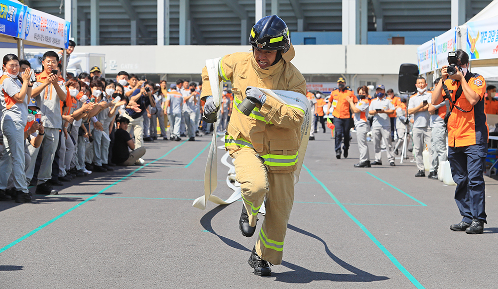 A member of Jeju Island's volunteer firefighting corps on Aug. 20 at Jeju Stadium in Jeju City runs while carrying a water hose in a skills contest for volunteer firefighters. 
