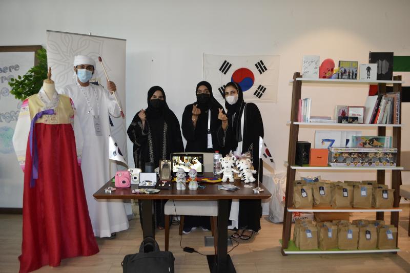 Three visitors take a group picture with the finger heart sign at the Korean booth of the Cultural Expo at Concept Plus in Al Quoz. 