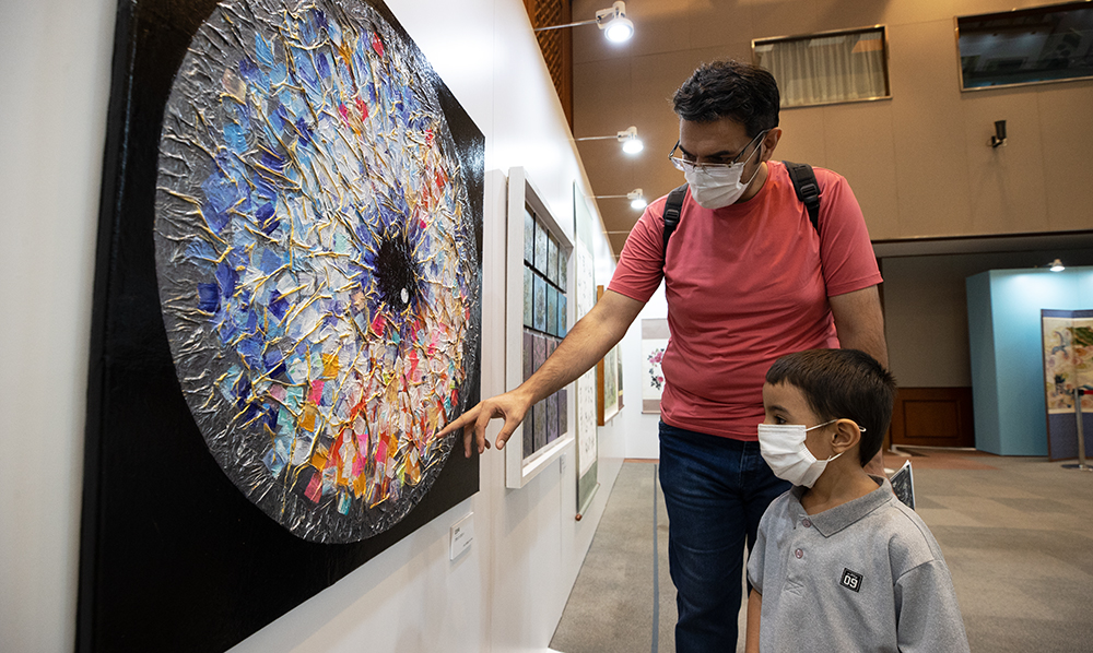 A foreign man and his son on Sept. 8 view an artwork at an exhibition for disabled artists titled 