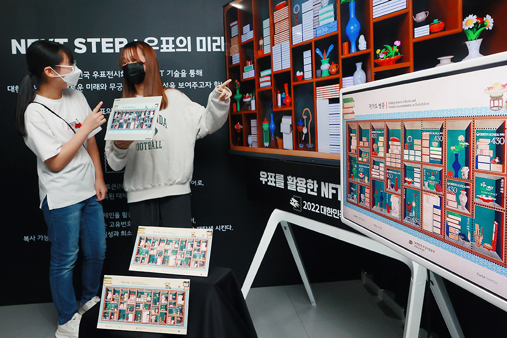 Two visitors on Sept. 22 look at non-fungible tokens (NFT) of postage stamps at this year's Korea Philatelic Exhibition held at Korea Postage Stamp Museum in Seoul's Jung-gu District.