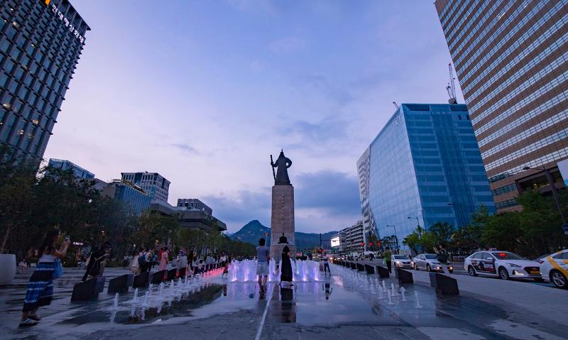Visitors to Gwanghwamun Square in Seoul stand around the fountain in front of the statue of Admiral Yi Sun-sin.