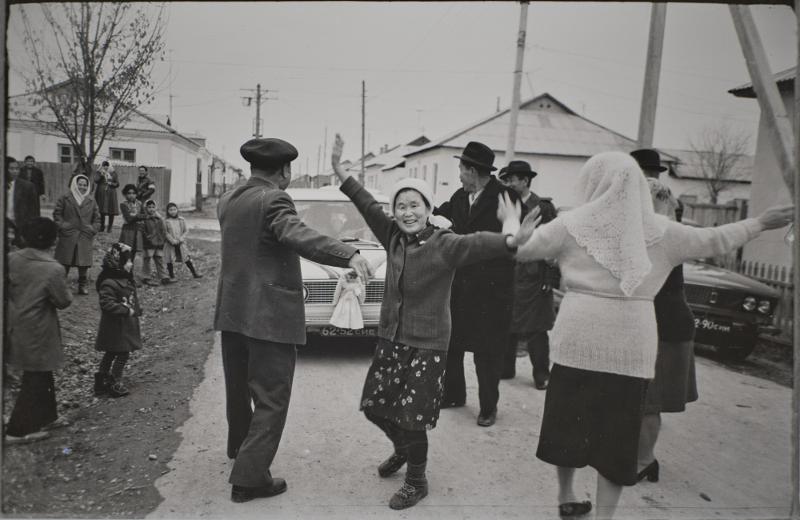 This photo of the wedding of Anatoliya An, taken in 1979 in Gulistan in Uzbekistan's Siraryo Viloyati province, shows the bride and groom ride in a car decorated with dolls and ribbons while the groom's family and relatives guide it and dance. (National Folk Museum of Korea) 