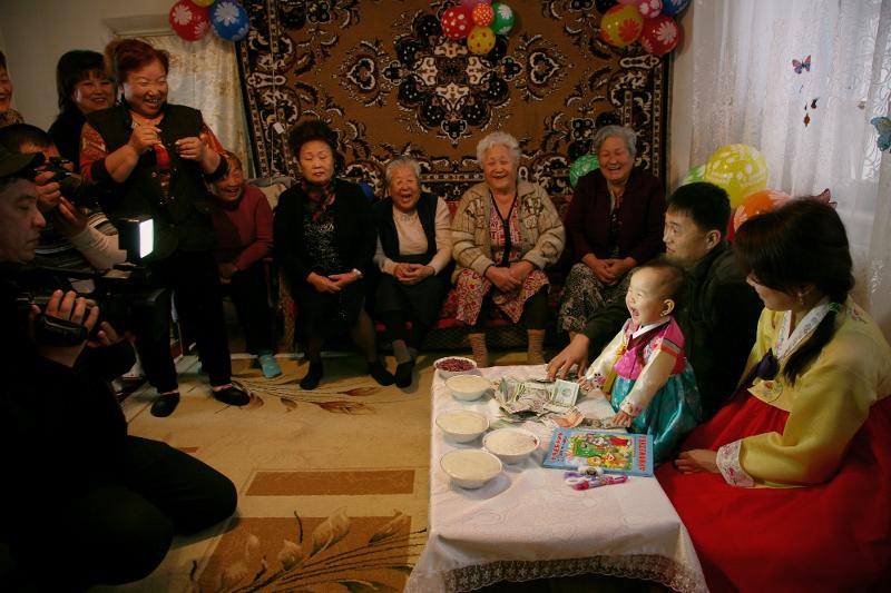 A baby's first birthday party is held in the village Soldatskoe in Uzbekistan's Tashkent province in a photo taken in 2015. Among Goryeoin rituals, such a party was least influenced by Russia or other neighboring countries. With Korea forming diplomatic ties with Uzbekistan in 1992, changes occurred such as the wearing of Hanbok (traditional attire) as the ceremonial attire for the party. (National Folk Museum of Korea) 