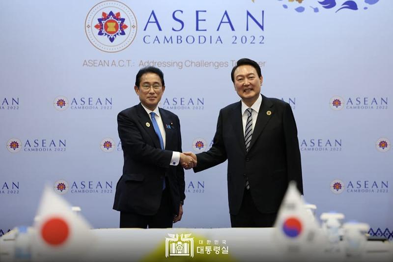 President Yoon Suk Yeol (right) on Nov. 13 shakes hands and poses for photos with Japanese Prime Minister Fumio Kishida at their bilateral summit held at a hotel in Phnom Penh, Cambodia.