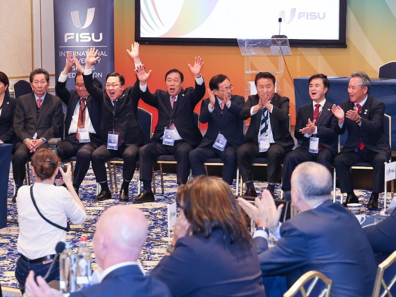 Daejeon Mayor Lee Jang Woo (third from left), Sejong Mayor Choi Min-ho (fourth from left), Chungcheongbuk-do Province Gov. Kim Young-hwan (third from right), Chungcheongnam-do Province Gov. Kim Tae-heum (second from right), and officials from the Ministry of Culture, Sports and Tourism and Korean Sport and Olympic Committee on Nov. 12 cheer after Korea won the right to host the 2027 Summer World University Games at the executive committee meeting of the International University Sports Federation in Brussels, Belgium. (Daejeon Metropolitan City) 