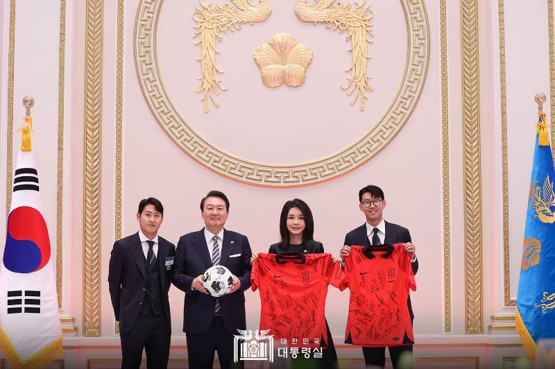 President Yoon Suk Yeol (second from left) and first lady Kim Keon Hee take a commemorative photo with national soccer team midfielder Lee Kang-in (left) and captain Son Heung-min (right) after receiving as gifts a soccer ball and uniforms signed by the squad at Yeongbingwan, the state guesthouse of the former presidential compound of Cheong Wa Dae. 