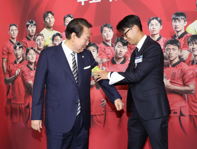 National soccer team captain Son Heung-min (right) on Dec. 8 fastens the armband that he wore at the Qatar World Cup on the arm of President Yoon Suk Yeol at the welcoming banquet hosted at Yeongbingwan, the state guesthouse of the former presidential compound of Cheong Wa Dae. (Yonhap News)