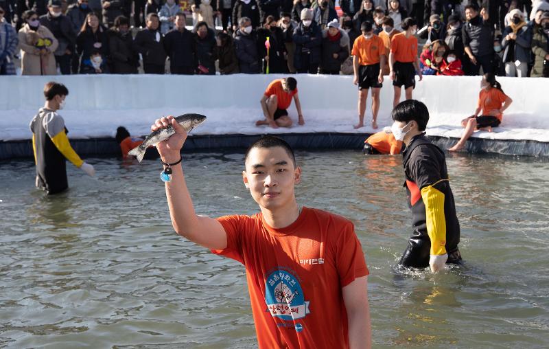 A visitors to the festival on the afternoon of Jan. 9 poses with a sancheoneo (mountain trout) after catching it with his bare hands at Hwacheoncheon Stream in the town of Hwacheon-eup in Hwacheon-gun County, Gangwon-do Province. (Kim Sunjoo)