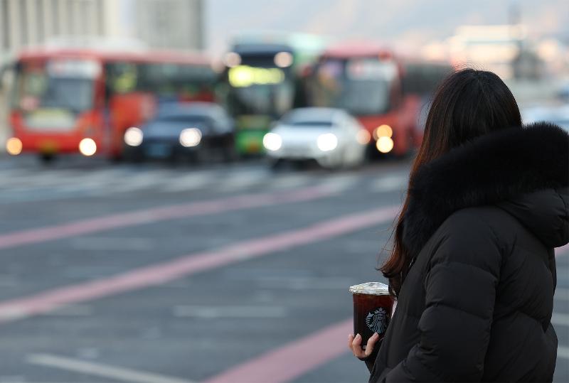 A person on Feb. 16, 2022, holds an iced Americano despite a frigid winter temperature of minus 11 degrees Celsius while waiting for the signal to change on a crosswalk in Seoul's Jongno-gu District. (Yonhap News)
