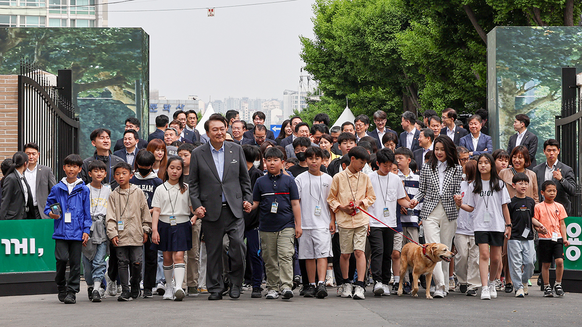 President Yoon Suk Yeol and first lady Kim Keon Hee on May 4 hold hands with children while entering Yongsan Children's Garden in Seoul's Yongsan-gu District to attend the facility's opening ceremony.