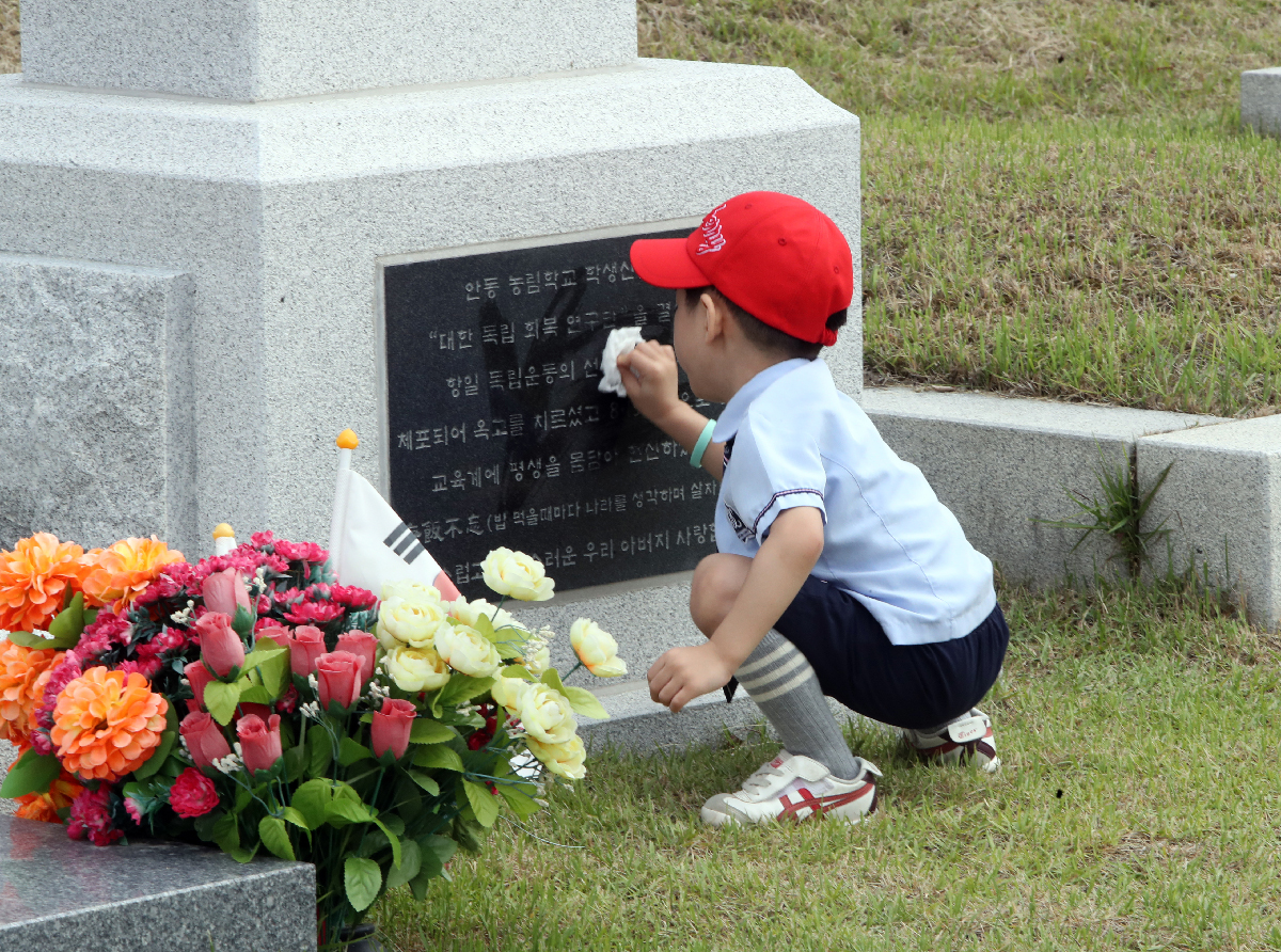A preschool student in Daejeon on the morning of June 2, four days before Memorial Day, polishes a patriot's headstone with a wet wipe at Daejeon National Cemetery in the city's Yuseong-gu District.