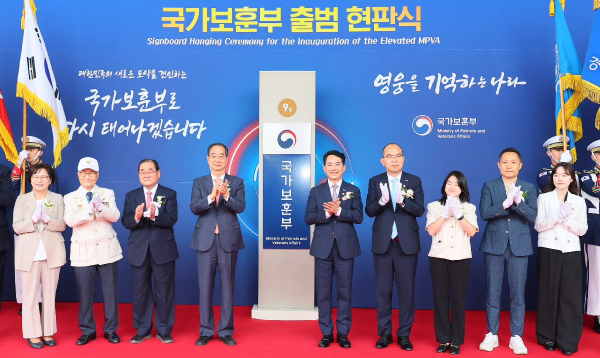 Prime Minister Han Duck-soo (fourth from left) on the morning of June 5 claps with Minister of Patriots and Veterans Affairs Park Minshik (fifth from left) while posing for a group photo after unveiling the signboard to mark the Ministry of Patriots and Veterans Affairs' promotion to full-fledged ministry status at a ceremony held at Government Complex-Sejong in Sejong.
