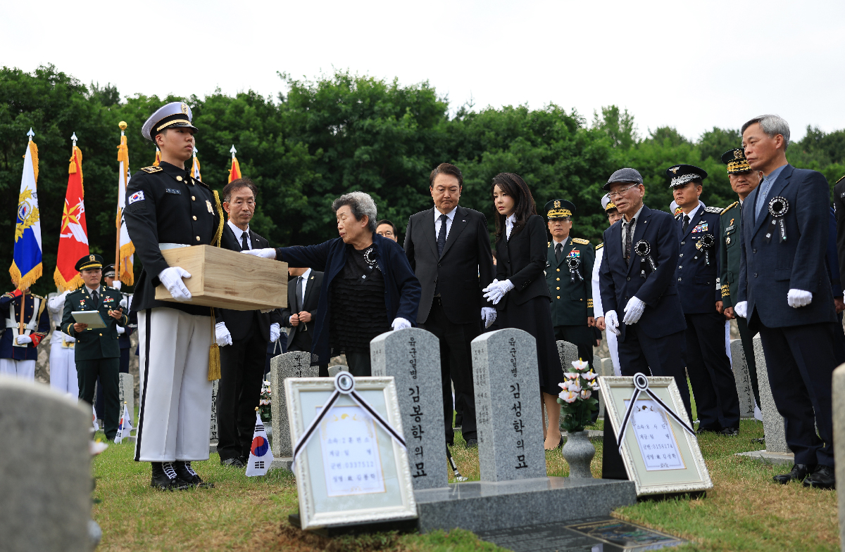 President Yoon Suk Yeol and first lady Kim Keon Hee on the morning of Memorial Day on June 6 watch a relative of Pvt. First Class Kim Bong-hak, who was killed during the Korean War, throw dirt on the patriot's casket at a burial ceremony held at the 52nd section of Seoul National Cemetery in the capital's Dongjak-gu District.