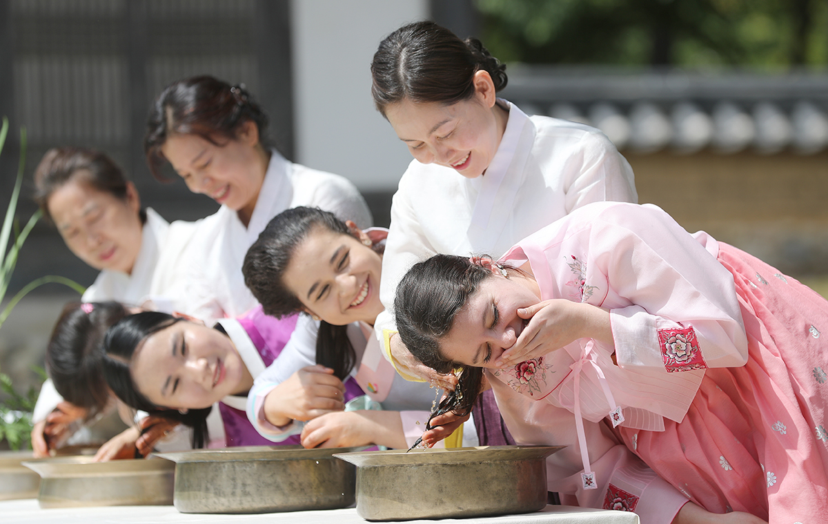 Foreign students on the morning of June 20, two days before Dano, one of Korea's three main traditional holidays that falls on May 5 in the lunar calendar, wash their hair in water mixed with leaves of the herb changpo (sweet iris) in the traditional Korean village of Yeungnam University in Gyeongsan, Gyeongsangbuk-do Province.