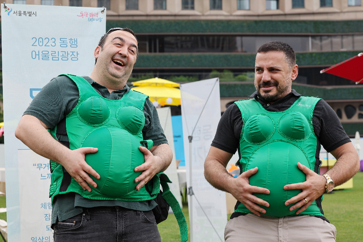 Tourists from Turkiye (Turkey) on June 23 wear clothes that partially simulate what pregnancy feels like at the event Hang Out Together Plaza (unofficial translation) held at Seoul Plaza in the capital's Jung-gu District.