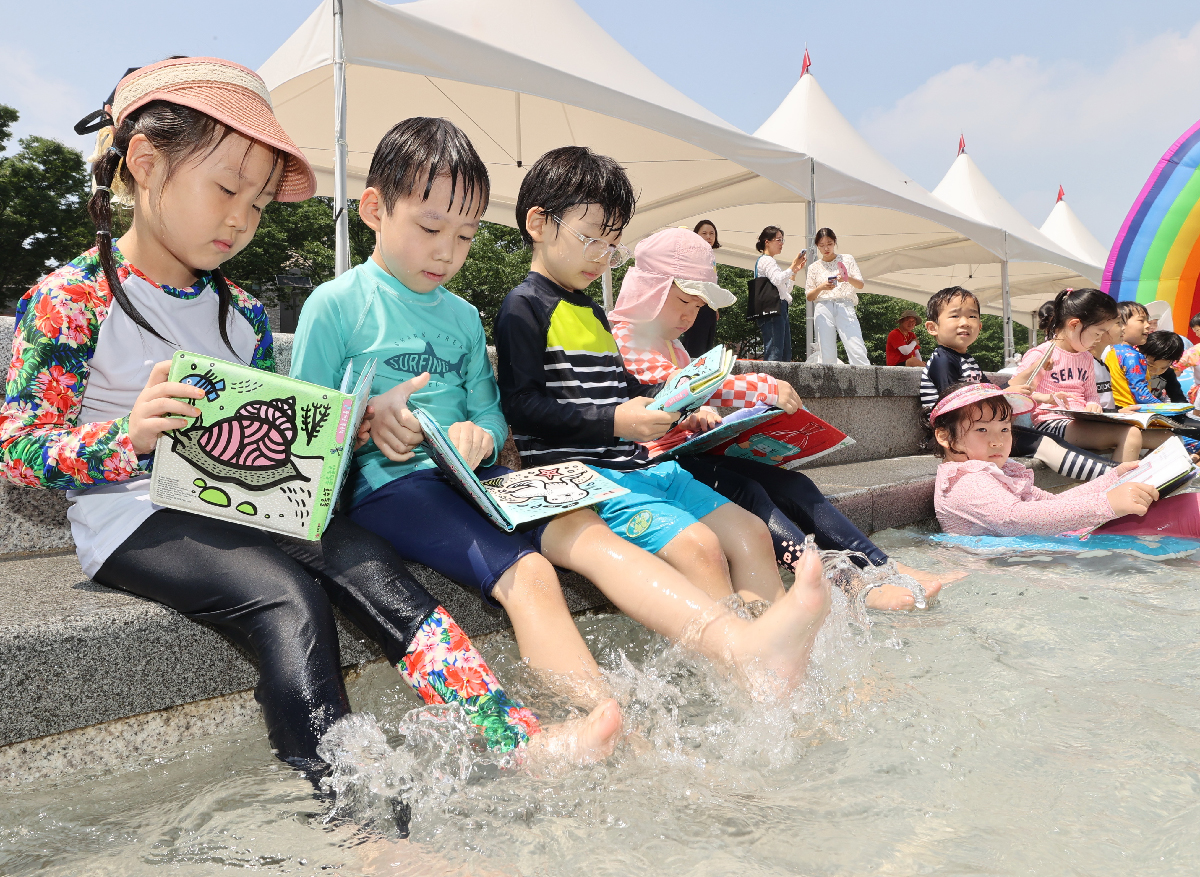 Children on the morning of July 21 read books at Seongnaecheon Stream Water Park in Seoul's Songpa-gu District.
