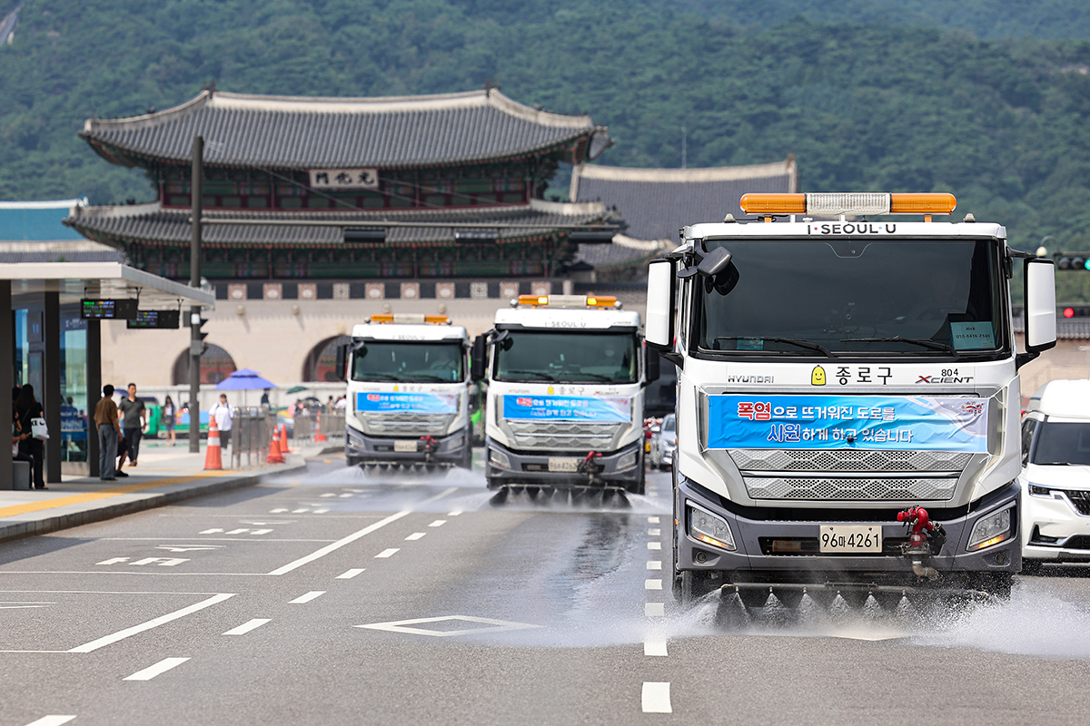 Street sweeper trucks on the afternoon of Aug. 2 spray water on Sejong-daero Road in Seoul's Jongno-gu District to ease the urban heat island effect, a phenomenon in which the temperature in a city center is higher than in the suburbs, to respond to the national heat wave.