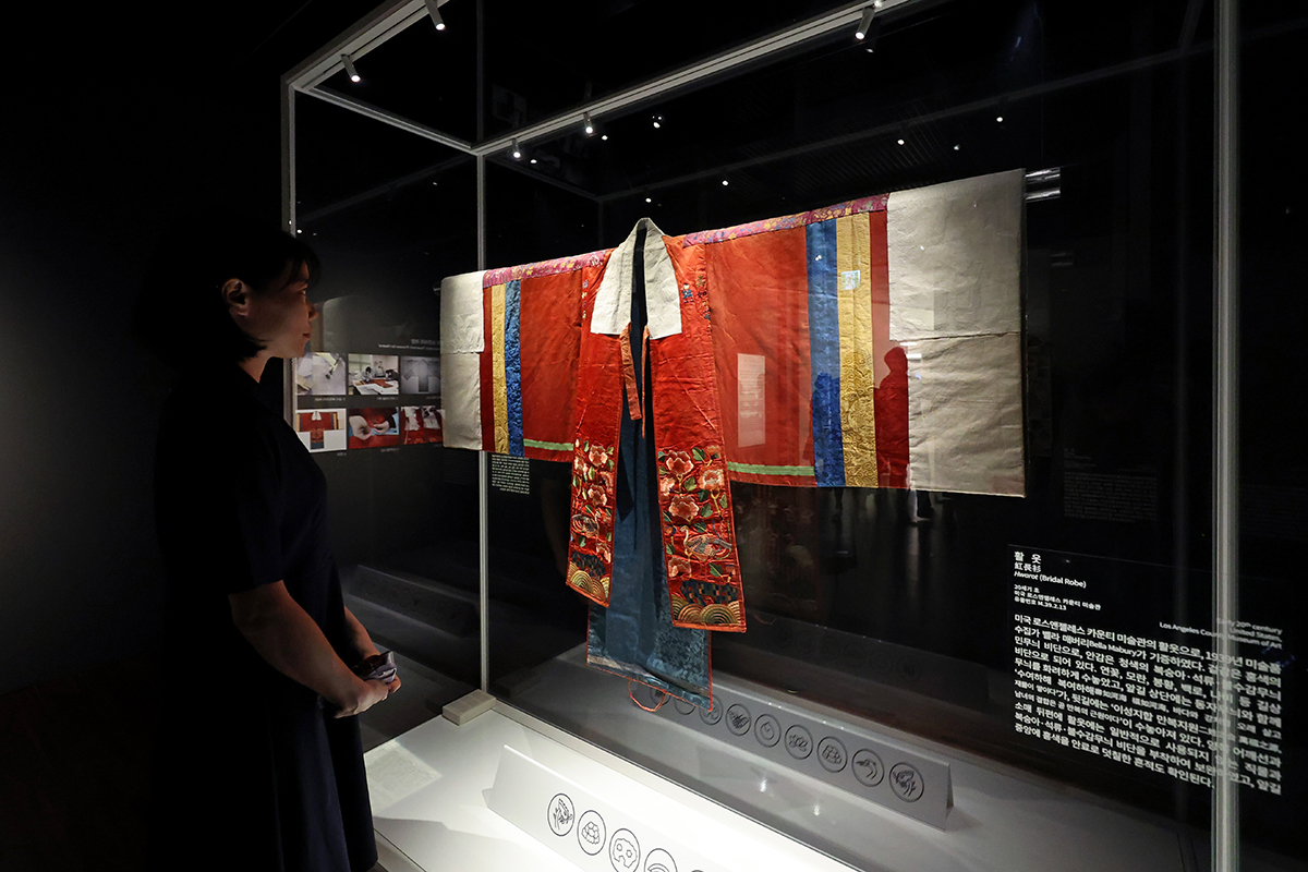 A visitor on the morning of Sept. 13 looks at a hwarot, an exquisite bridal gown worn by women of the royal court during the Joseon Dynasty, at a media event for the exhibition 