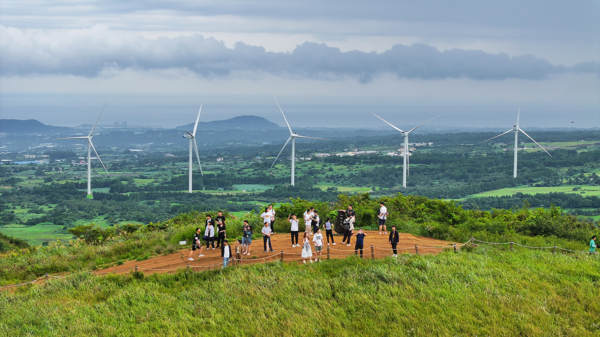 Tourists on the morning of Sept. 14 enjoy a scenic view of Jeju Island at the top of the volcanic cone Saebyeol Oreum in the village of Bongsung-ri of the town of Aewol-eup. The cone is the leading one of its kind on the island's western region and gets its name from its lonely appearance resembling a shooting star in the evening sky.
