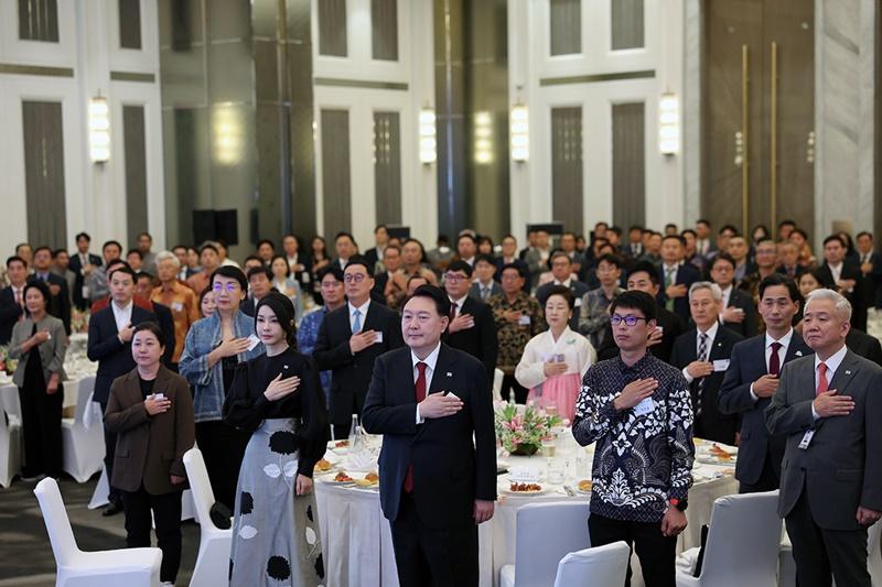 President Yoon Suk Yeol (third from left in front row) and first lady Kim Keon Hee (second from left in front row) on Sept. 5 stand in salute while listening to the Korean national anthem at a dinner for Korean expats in Indonesia at a hotel in Jakarta. (Jeon Han) 