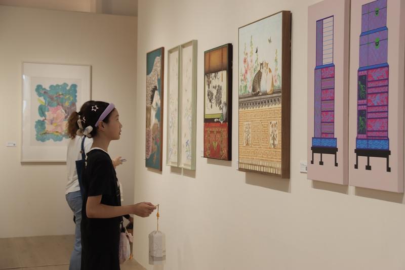 Visitors on Aug. 12 look at artworks shown at 