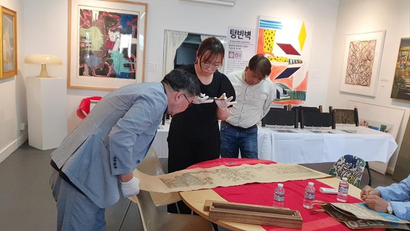 Researcher Jina Nam (center) on Sept. 5 appraises cultural assets at an exhibition of reclaimed cultural heritage at Leesu Gallery in Los Angeles' Korea town. (Jina Nam)