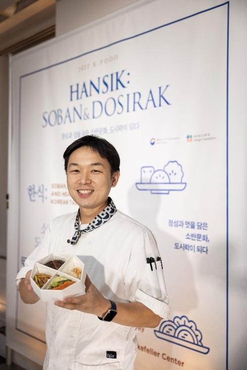 Chef Kim Han-song shows a dosirak (lunch box) featuring the leading Korean holiday dishes ssambap, japchae, tteokgalbi (grilled short-rib patties), jeon (pancake) and baek (white) kimchi at the event 