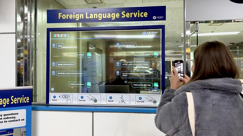Turkish tourist Kardelen Kose on Dec. 12 takes a photo of the AI Live-Translation System at Myeongdong Station in Seoul.