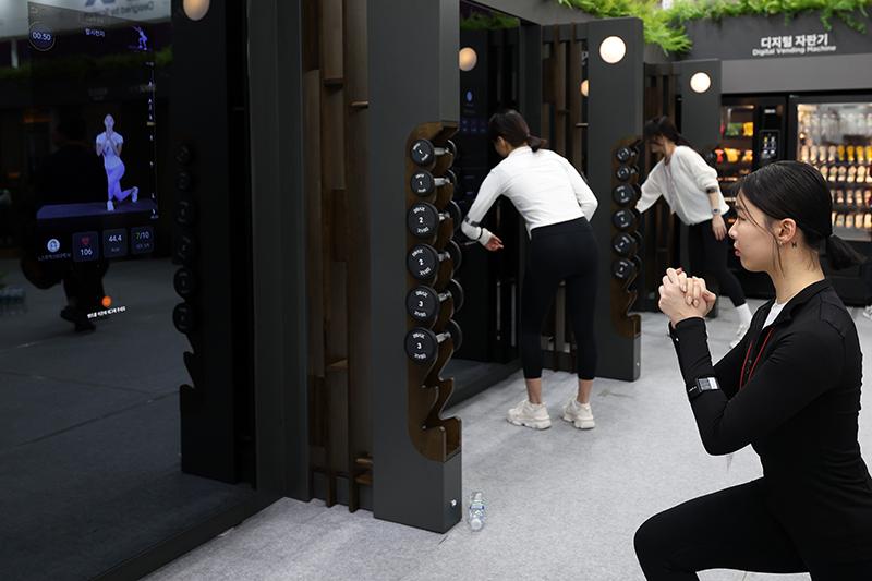 A fitness trainer on Feb. 22 demonstrates a personalized workout with guidance from a high-tech digital smart mirror on the opening day of the Seoul International Sports & Leisure Industry Show, aka SPOEX 2024, at DRAX Pavilion of COEX Mall in Seoul's Gangnam-gu District.