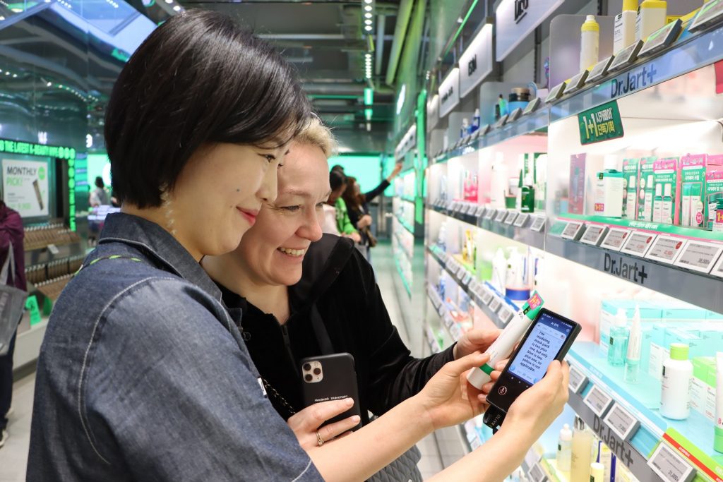 A worker at the Myeong-dong branch of the beauty and health product franchise CJ Olive Young in Seoul communicates with a foreign customer through a portable translation device. (CJ Olive Young) 