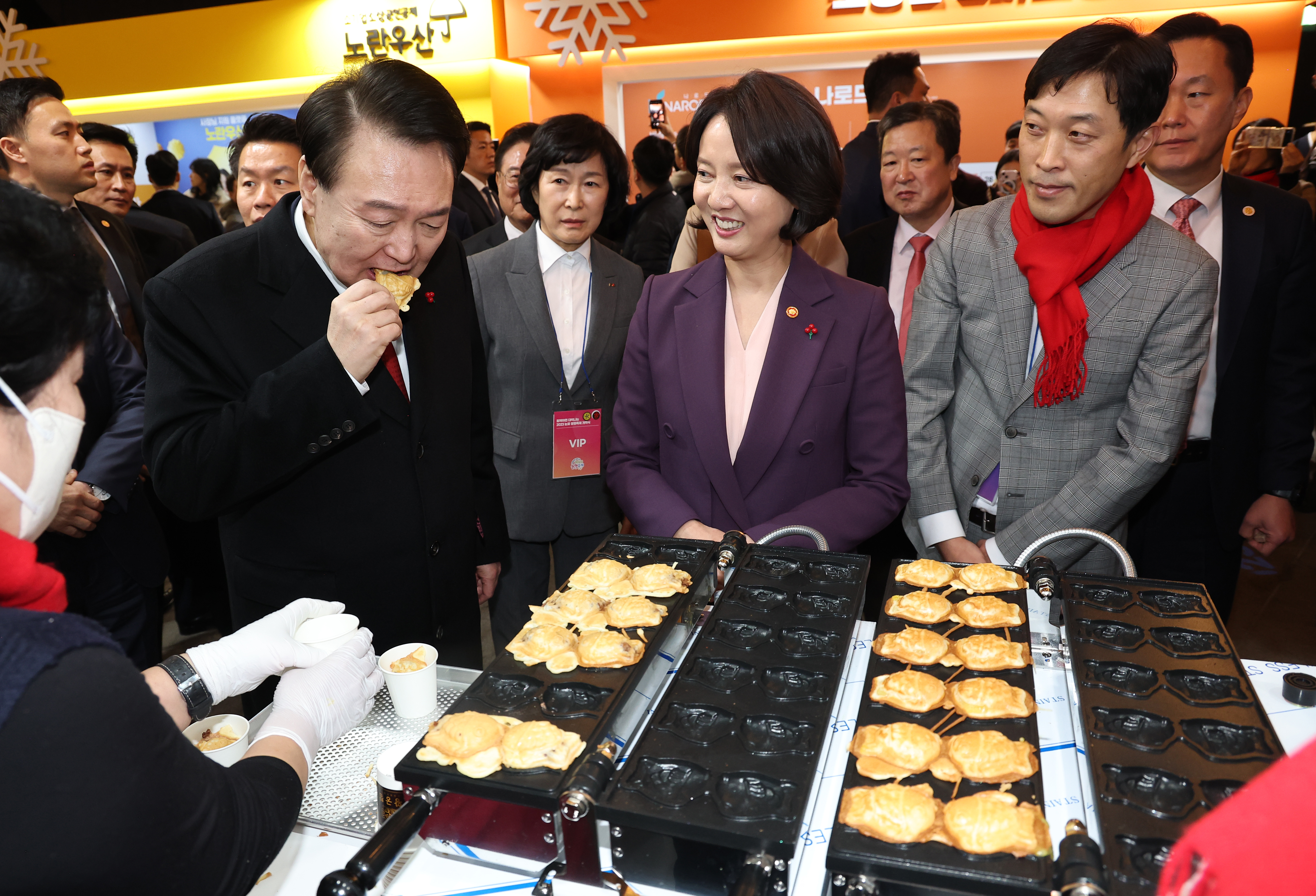 President Yoon on Dec. 7, 2023, tastes bungeoppang, or a fish-shaped pastry with sweet red bean paste filling, made by the National Cafe Owner Cooperative Organization at the Snow Flower K-shopping Festa at Dongdaemun Design Plaza in Seoul's Jung-gu District. .
