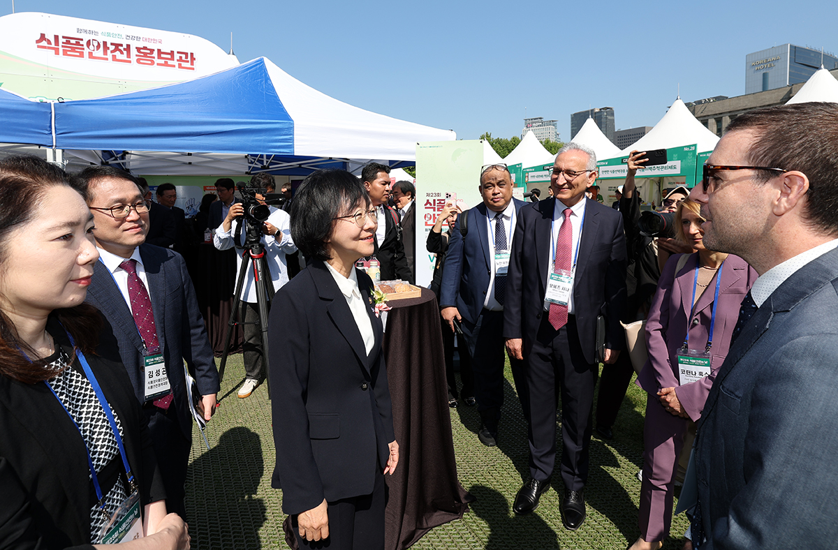 Minister of Food and Drug Safety Oh Yu-Kyoung on May 13 (third from left) talks with Diego Jose Varela Maino (far right), executive secretary of the Chilean Agency for Food Safety and Quality, aka ACHIPIA, while visiting booths promoting food safety at Seoul Plaza in the capital's Jung-gu District the day before Food Safety Day. Set up by the Korean government, consumer groups and food companies, the booths will run through May 14 to provide useful related information to the public.