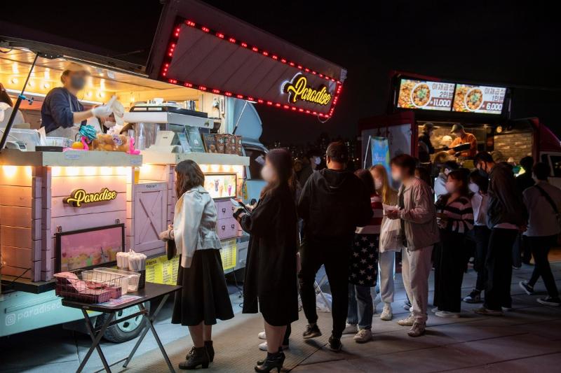 People in June 2023 line up in front of food trucks at the Hangang Moon Light Market held at Banpo Hangang River Park in Seoul's Seocho-gu District.