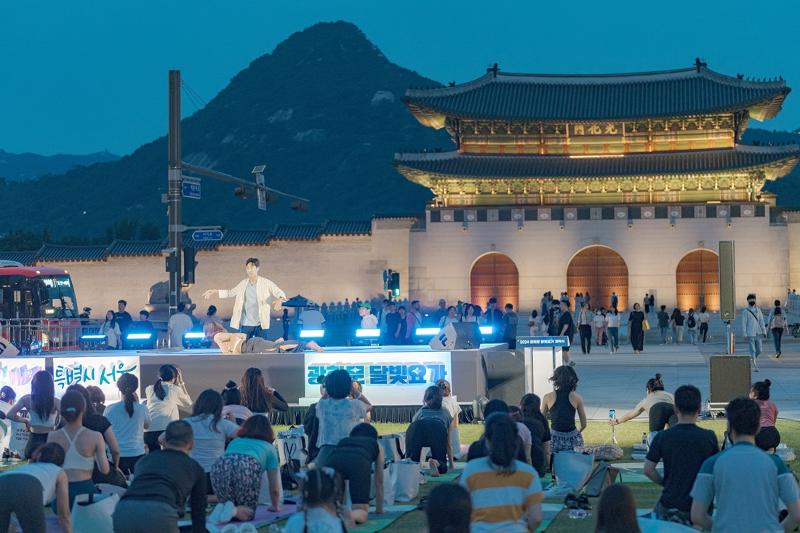 A yoga instructor on June 21 teaches the discipline to yogis at Yukjo Madang of Gwanghwamun Square in Seoul's Jongno-gu District. (Seoul Metropolitan Government)
