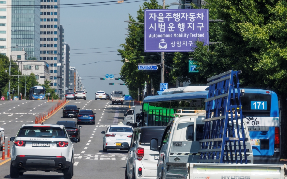 Vehicles on June 13 travel on a road with a sign on the pilot operation of self-driving cars in the Sangam-dong neighborhood of Seoul's Mapo-gu District. (Yonhap News)