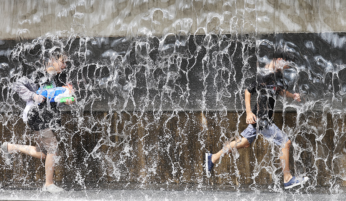 Students on the morning of July 30, when a heat wave warning was issued nationwide, cool off by playing around a water fountain at Gwanggyo Lake Park in Yeongtong-gu District of Suwon, Gyeonggi-do Province.