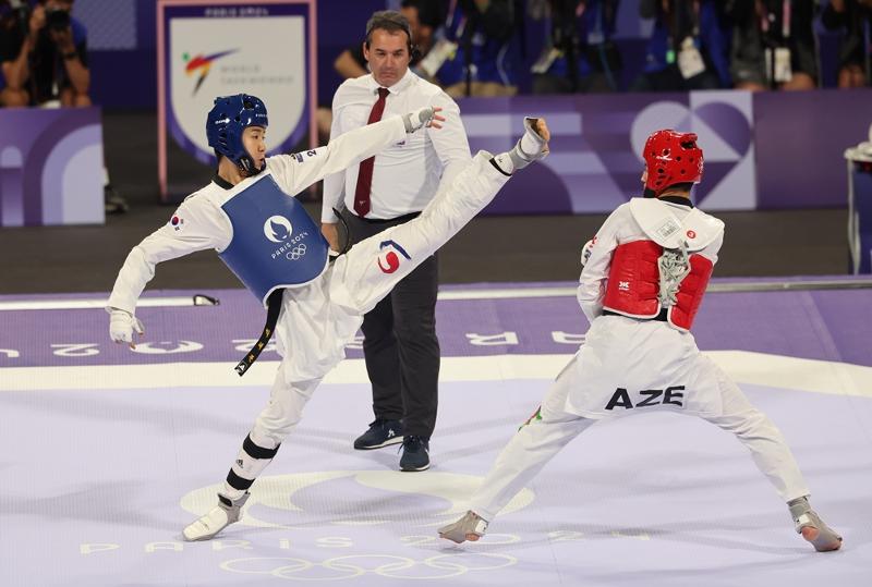 National taekwondo competitor Park Taejoon (left) on Aug. 7 throws a kick against Azerbaijan's Gashim Magomedov in the final of the men's 58-kg class at the Paris Summer Olympics held at the Grand Palais in the French capital.