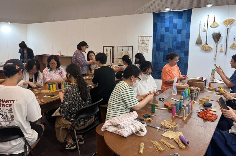 Visitors to this year's Hanbok Expo on Aug. 9 make brooms with mosi (natural ramie fiber) at an interactive event. (Israa Mohamed)  