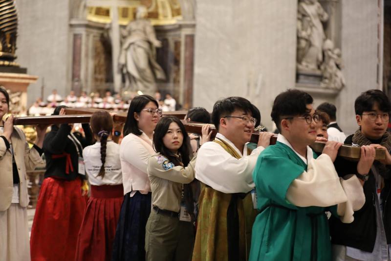 Youths from Korea on Nov. 24 receive the wooden cross, a symbol of World Youth Day, from their Portuguese counterparts at St. Peter's Basilica in Vatican City.