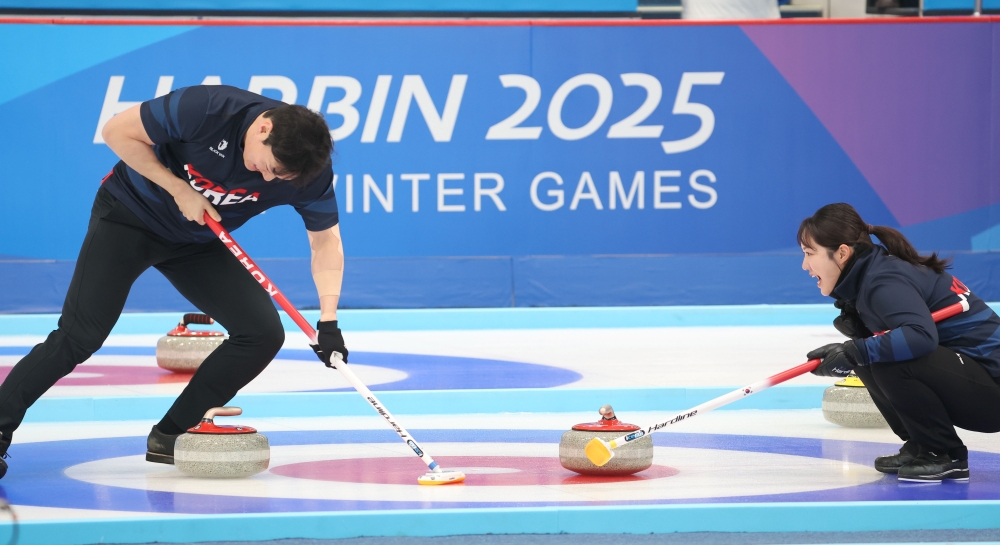 Seong Jihoon of the national mixed doubles curling team on Feb. 6 does a sweep in a Group B match against China at Harbin Pingfang District Curling Arena in Harbin, China.
